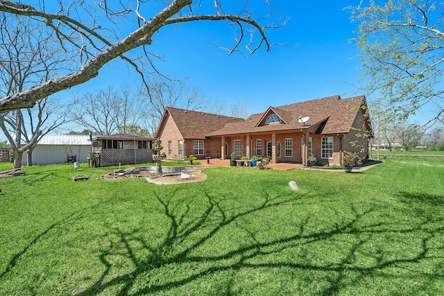rear view of property with a patio area, brick siding, and a yard