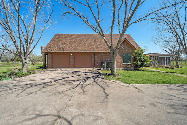 view of front of house featuring a garage, concrete driveway, brick siding, a front lawn, and cooling unit