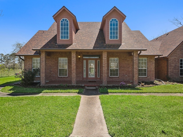 view of front of property with brick siding, a front yard, and a shingled roof
