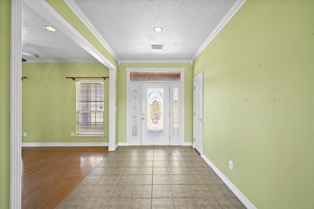 foyer entrance with baseboards, a textured ceiling, tile patterned flooring, and crown molding