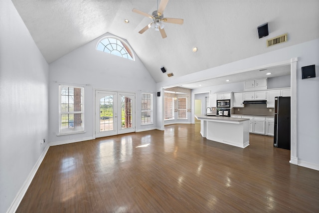 unfurnished living room with high vaulted ceiling, visible vents, baseboards, ceiling fan, and dark wood finished floors