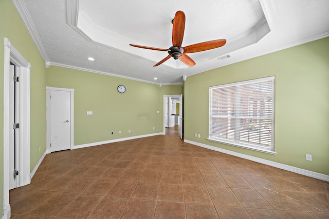 empty room featuring a textured ceiling, crown molding, baseboards, ceiling fan, and a raised ceiling