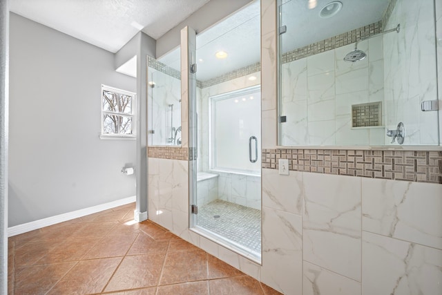 bathroom with tile patterned floors, baseboards, and a marble finish shower