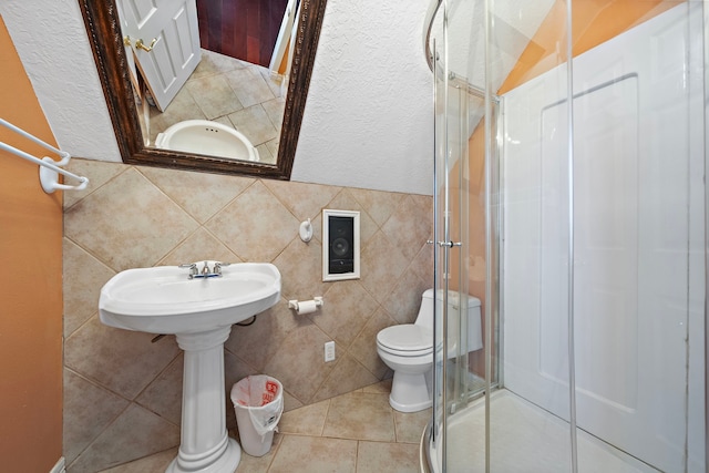 bathroom featuring tile walls, toilet, a stall shower, and tile patterned flooring