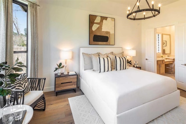 bedroom featuring baseboards, connected bathroom, a chandelier, and wood finished floors