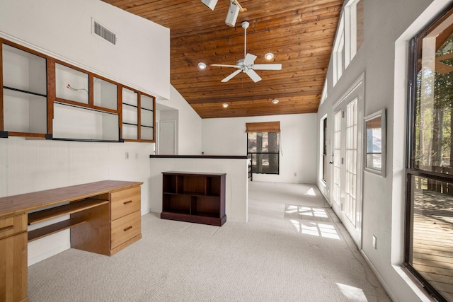 unfurnished office featuring wood ceiling, a towering ceiling, light colored carpet, and ceiling fan