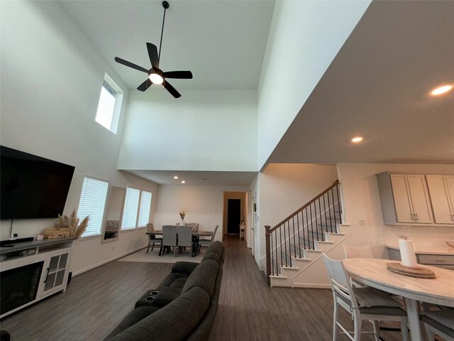 2412 Elliott Shore Ln, La Porte, TX 77571 - living room featuring dark wood-style flooring, baseboards, stairs, ceiling fan, and a high ceiling