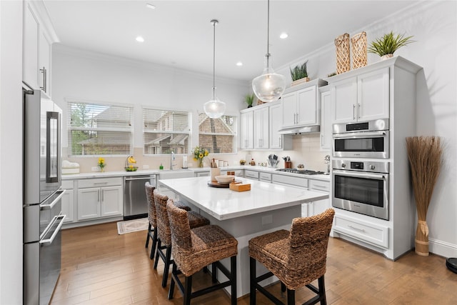 106 Golden Eye Ct, Montgomery, TX 77316 - kitchen with stainless steel appliances, ornamental molding, a sink, a kitchen bar, and light countertops