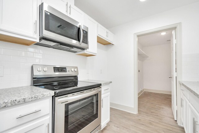 1501 Maiden Ln, Richmond, TX 77469 - kitchen featuring backsplash, light wood-style flooring, stainless steel appliances, and white cabinetry