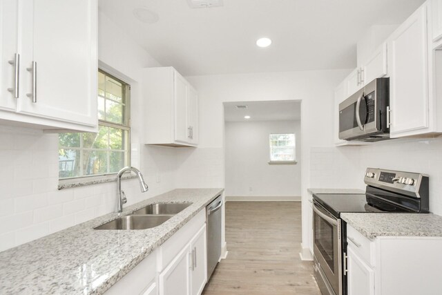 1501 Maiden Ln, Richmond, TX 77469 - kitchen with a wealth of natural light, white cabinetry, a sink, and stainless steel appliances