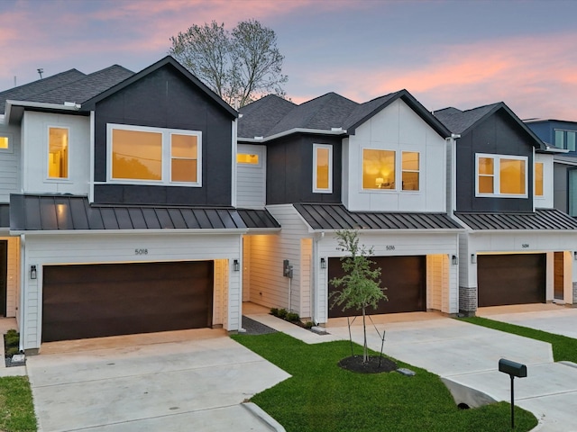 multi unit property featuring concrete driveway, an attached garage, and a standing seam roof