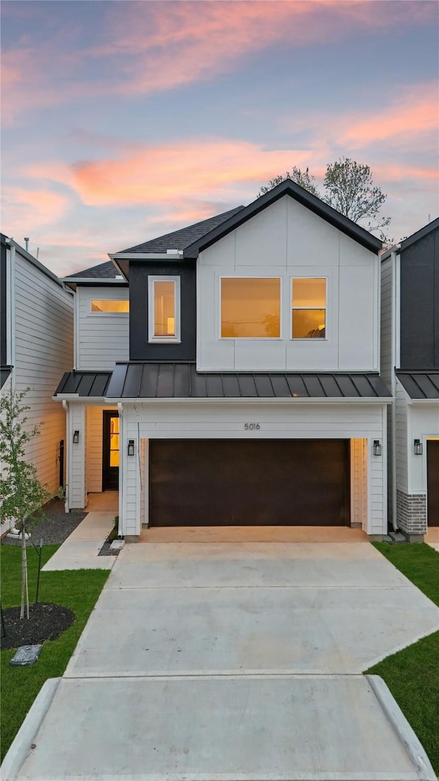 modern farmhouse featuring a standing seam roof, metal roof, driveway, an attached garage, and a shingled roof