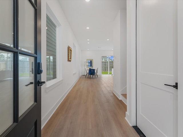 corridor featuring baseboards, recessed lighting, and light wood-style flooring