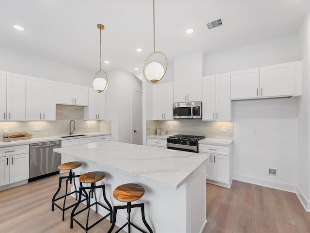 kitchen with a kitchen island, stainless steel appliances, decorative backsplash, and a sink