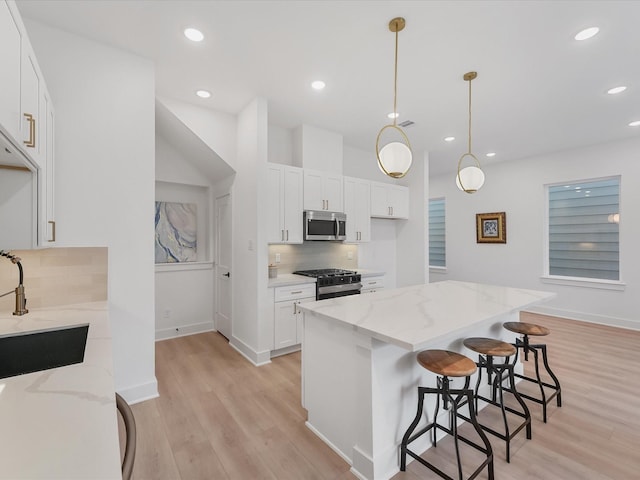 kitchen featuring backsplash, stainless steel microwave, light wood-type flooring, and gas range