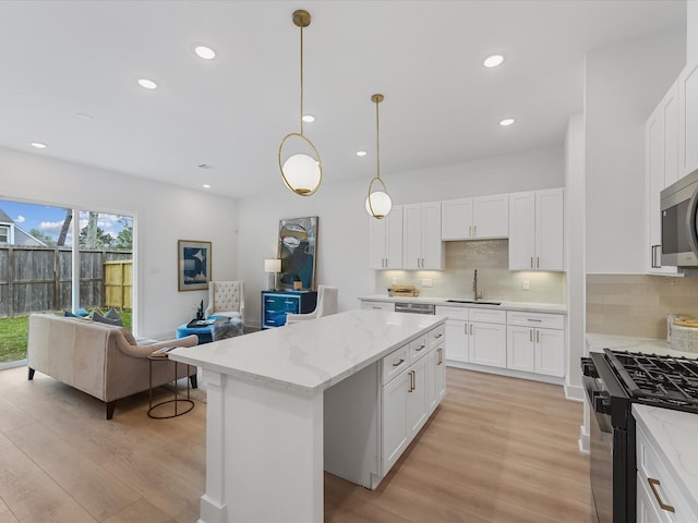 kitchen featuring stainless steel appliances, a sink, light wood-style flooring, and tasteful backsplash