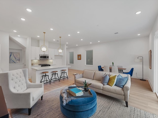 living room with light wood-type flooring, recessed lighting, and baseboards