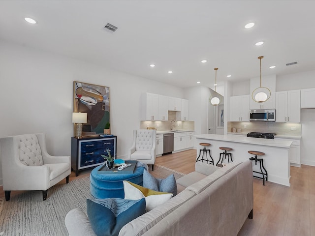 living area featuring visible vents, recessed lighting, and light wood-style floors