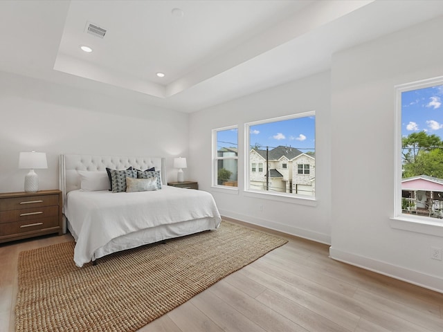 bedroom with visible vents, a raised ceiling, baseboards, recessed lighting, and light wood-style flooring