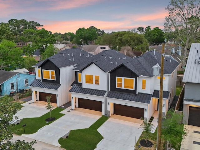 modern farmhouse style home featuring concrete driveway, a garage, roof with shingles, and a standing seam roof