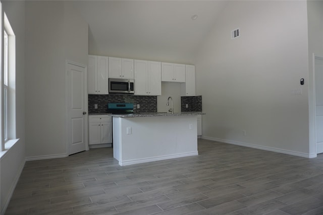14848 Lamar Rd, Willis, TX 77378 - kitchen featuring visible vents, high vaulted ceiling, white cabinets, tasteful backsplash, and appliances with stainless steel finishes
