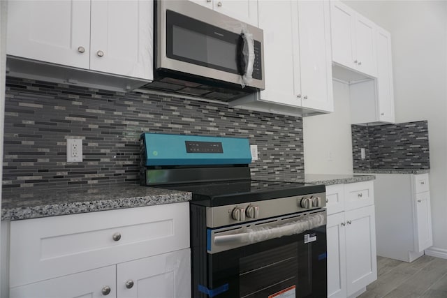 14848 Lamar Rd, Willis, TX 77378 - kitchen featuring white cabinets, light wood finished floors, stone countertops, stainless steel appliances, and backsplash