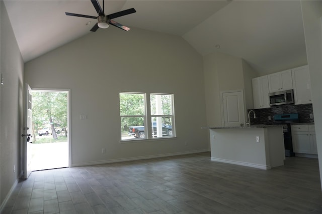 14848 Lamar Rd, Willis, TX 77378 - kitchen with a ceiling fan, high vaulted ceiling, open floor plan, stainless steel appliances, and white cabinetry