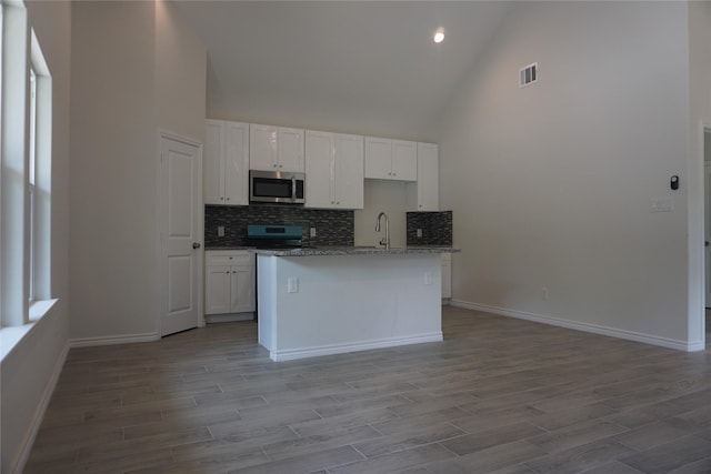 14848 Lamar Rd, Willis, TX 77378 - kitchen featuring white cabinets, a sink, high vaulted ceiling, stainless steel appliances, and tasteful backsplash