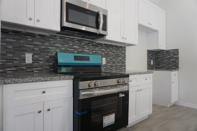 14848 Lamar Rd, Willis, TX 77378 - kitchen featuring light wood-style floors, stone counters, appliances with stainless steel finishes, and backsplash