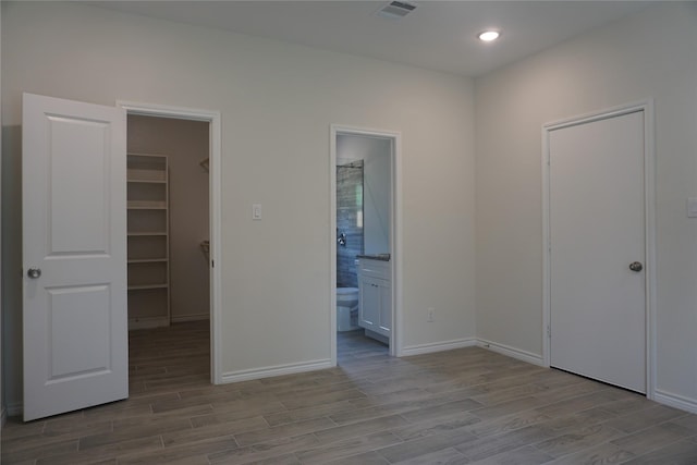 14848 Lamar Rd, Willis, TX 77378 - unfurnished bedroom with visible vents, a closet, wood finished floors, a walk in closet, and ensuite bath