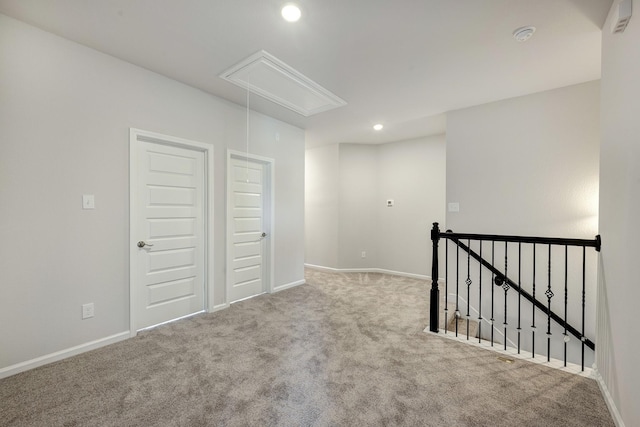 carpeted spare room featuring recessed lighting, attic access, and baseboards