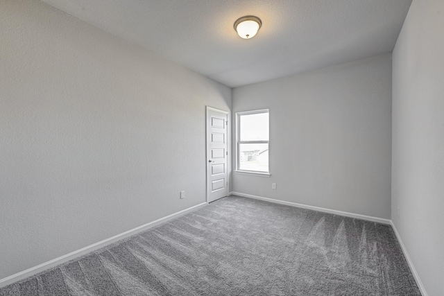 carpeted empty room featuring baseboards