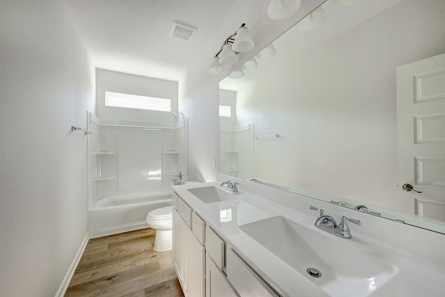 bathroom featuring toilet, a sink, shower / bathing tub combination, and wood finished floors