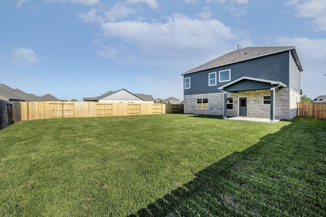 back of house with a fenced backyard, a yard, a patio area, and brick siding