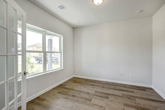 empty room featuring baseboards, visible vents, and wood finished floors