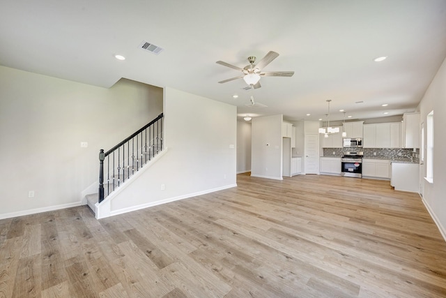 unfurnished living room featuring stairway, baseboards, ceiling fan with notable chandelier, recessed lighting, and light wood-style flooring