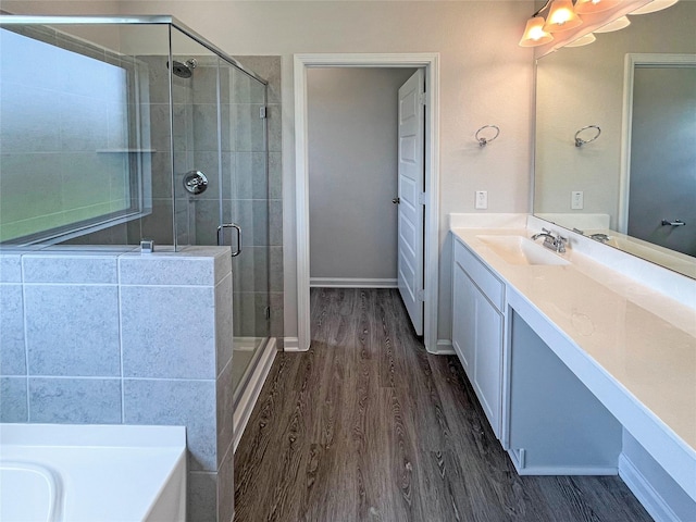 full bathroom featuring wood finished floors, a shower stall, vanity, and baseboards