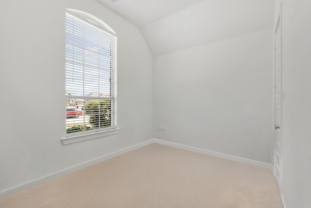 empty room with light carpet, baseboards, and lofted ceiling