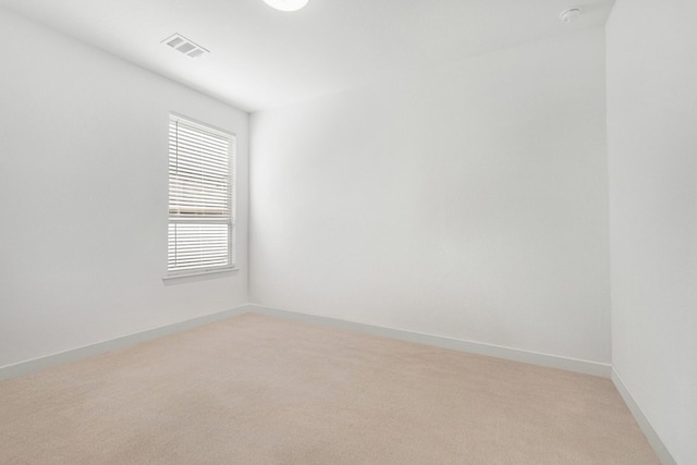 empty room featuring light colored carpet, visible vents, and baseboards