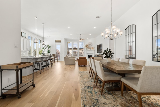 dining room with recessed lighting, ceiling fan with notable chandelier, light wood-style floors, visible vents, and a fireplace