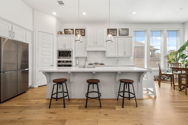 kitchen featuring white cabinetry, decorative backsplash, a sink, visible vents, and appliances with stainless steel finishes