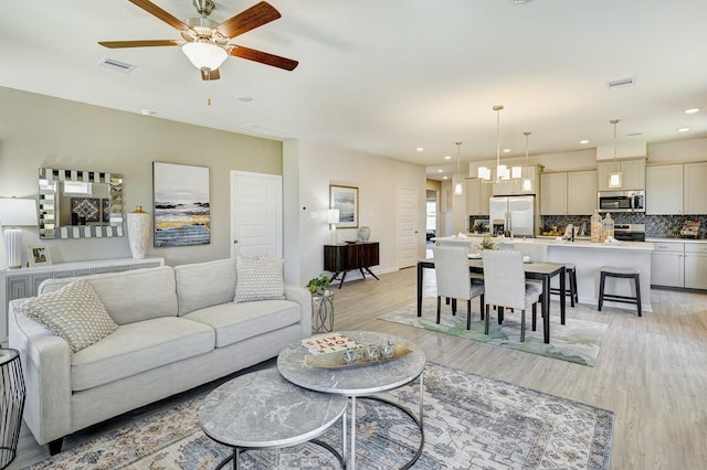 672 Woodhaven Lakes Dr, La Marque, TX 77568 - living room with light wood-style flooring, ceiling fan, and visible vents