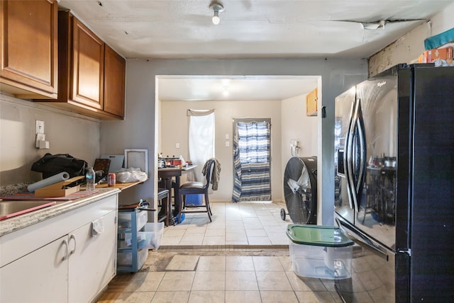 13022 Gladden Dr, Houston, TX 77049 - kitchen with light countertops, light tile patterned floors, black fridge with ice dispenser, and brown cabinetry