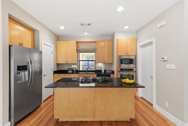 4406 Spencer St Unit A, Houston, TX 77007 - kitchen featuring stainless steel appliances, light brown cabinets, light wood finished floors, a sink, and a kitchen island