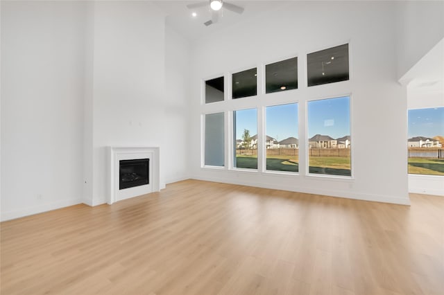 1559 River Point Dr, Friendswood, TX 77546 - unfurnished living room with a towering ceiling, a fireplace, a ceiling fan, light wood-type flooring, and baseboards