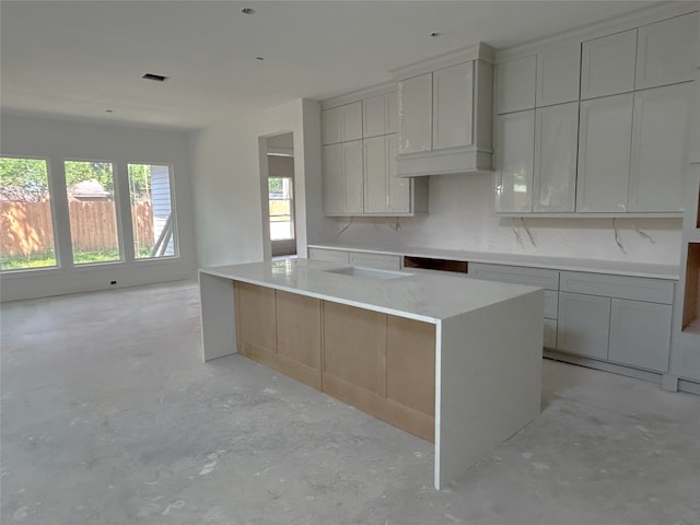 kitchen with a center island, light countertops, unfinished concrete floors, and visible vents
