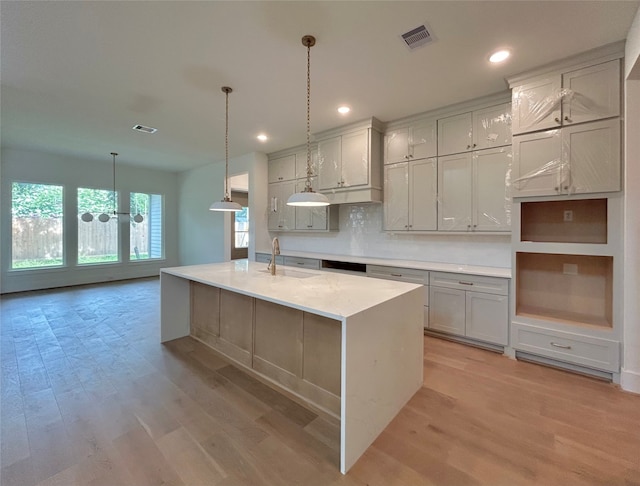 1905 Norcrest Dr, Houston, TX 77055 - kitchen with light wood-style flooring, recessed lighting, a kitchen island with sink, backsplash, and decorative light fixtures