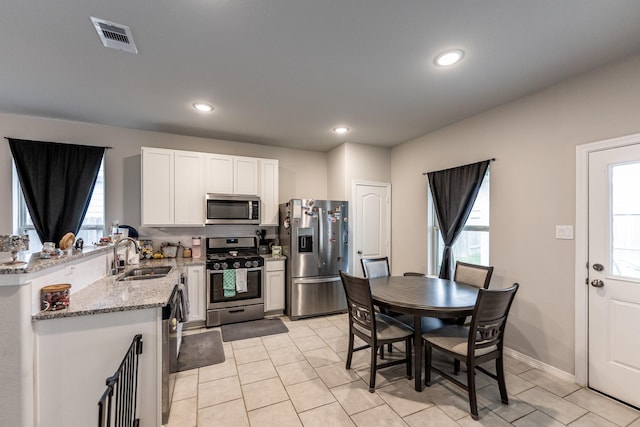 25843 Hickory Pecan Trl, Tomball, TX 77375 - kitchen with stainless steel appliances, a sink, light stone counters, light tile patterned floors, and a peninsula