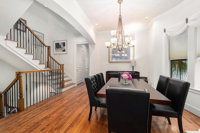 dining room featuring a notable chandelier, baseboards, ornamental molding, stairway, and wood finished floors