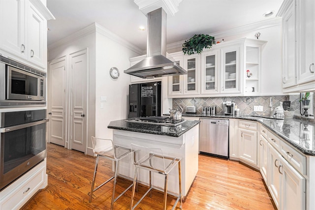 kitchen with island range hood, a center island, appliances with stainless steel finishes, and white cabinets